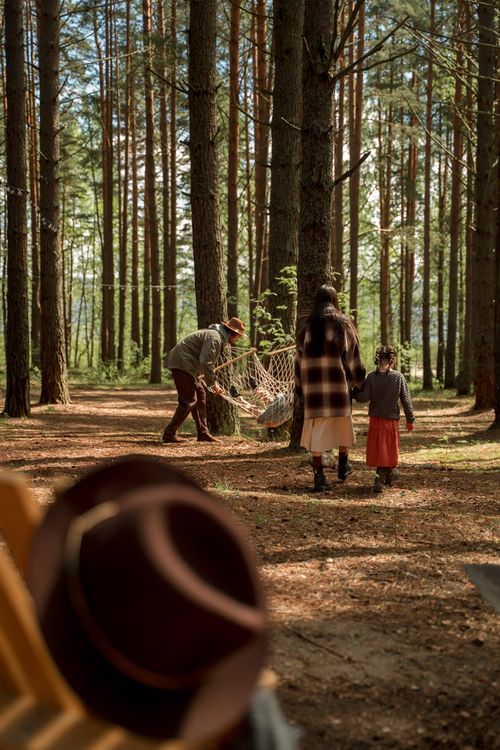 Free A family enjoys a serene walk in the woods, setting up a hammock for relaxation. Stock Photo