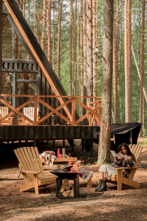 Woman sitting on a Wooden Chair near Wooden Cabin 