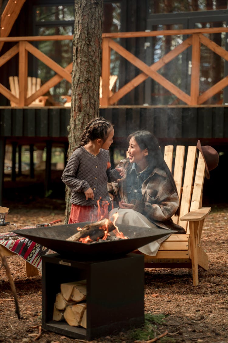 A Woman Talking To Her Daughter Near A Campfire