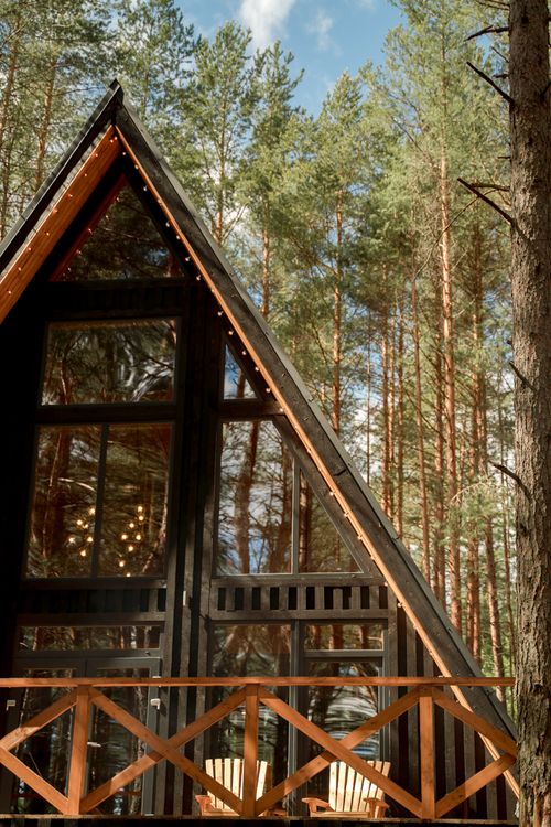 Free A charming A-frame cabin surrounded by dense forest trees, showcasing nature's beauty. Stock Photo
