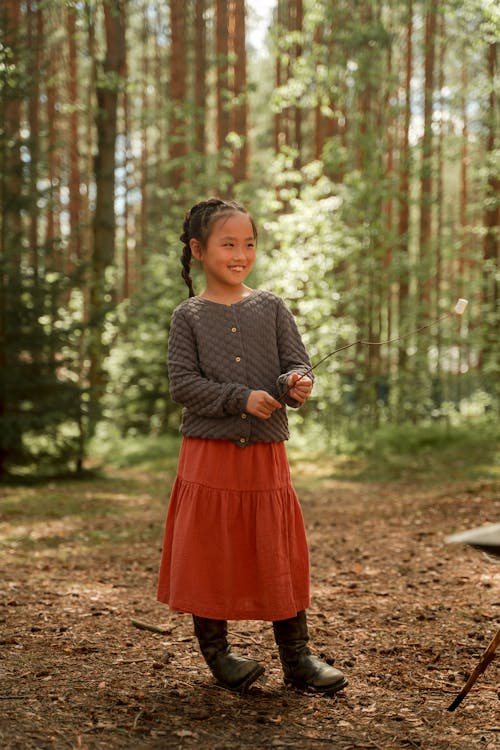 Free A Happy Girl Standing in the Woods while Holding a Stick Stock Photo
