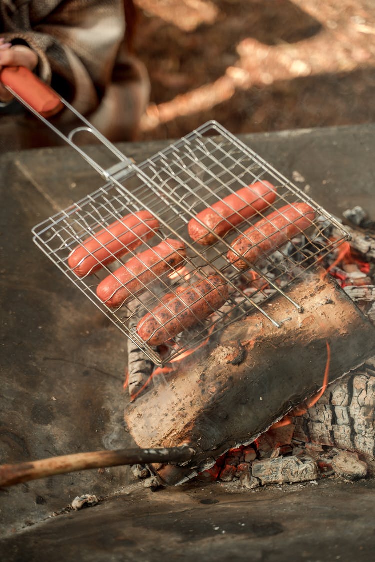 A Person Grilling Sausages In A Griller