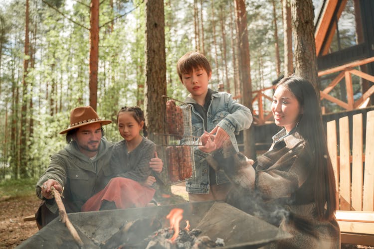 A Family Grilling Food On Bonfire