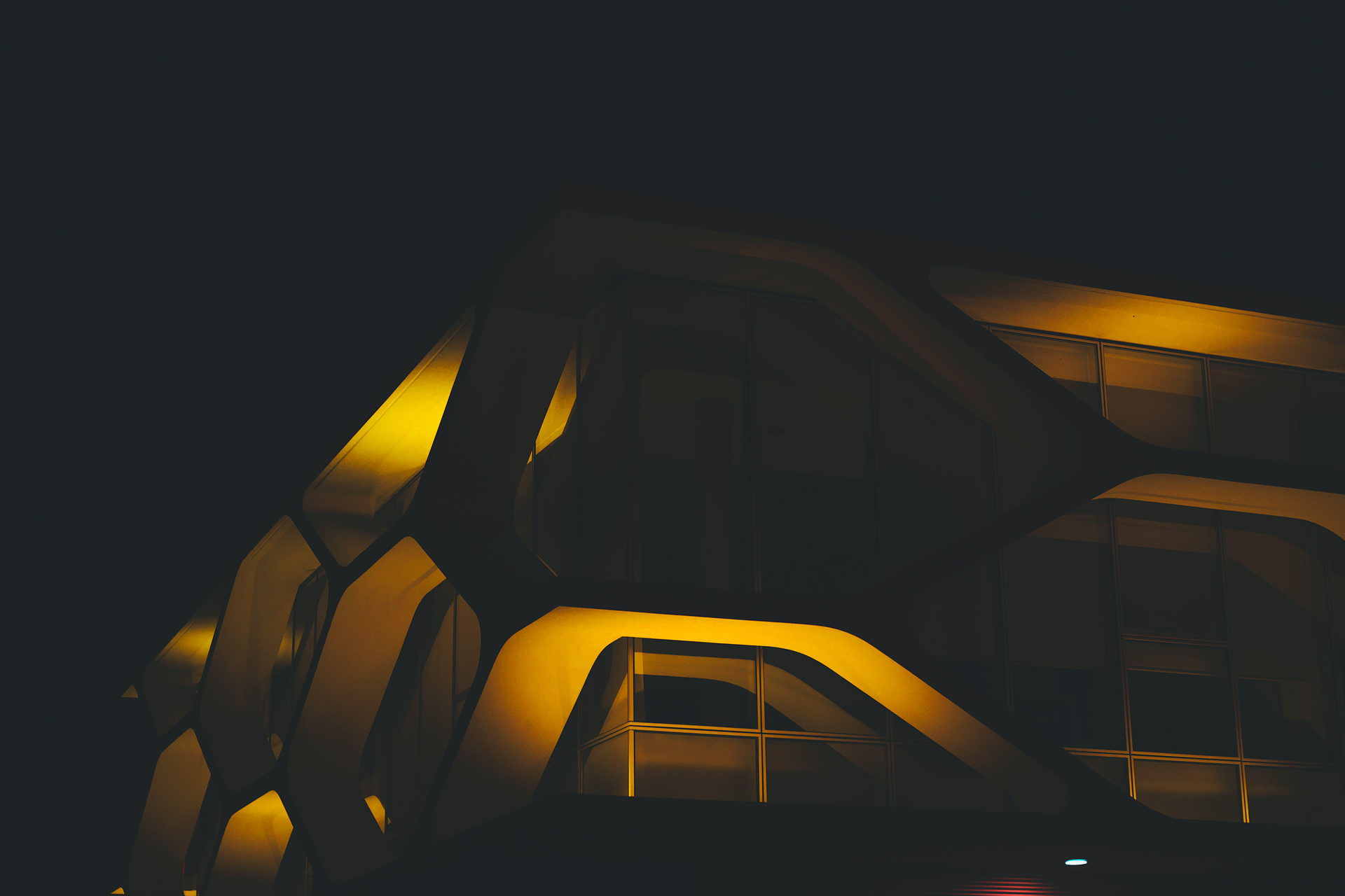 An illuminated modern building with futuristic design captured at night
