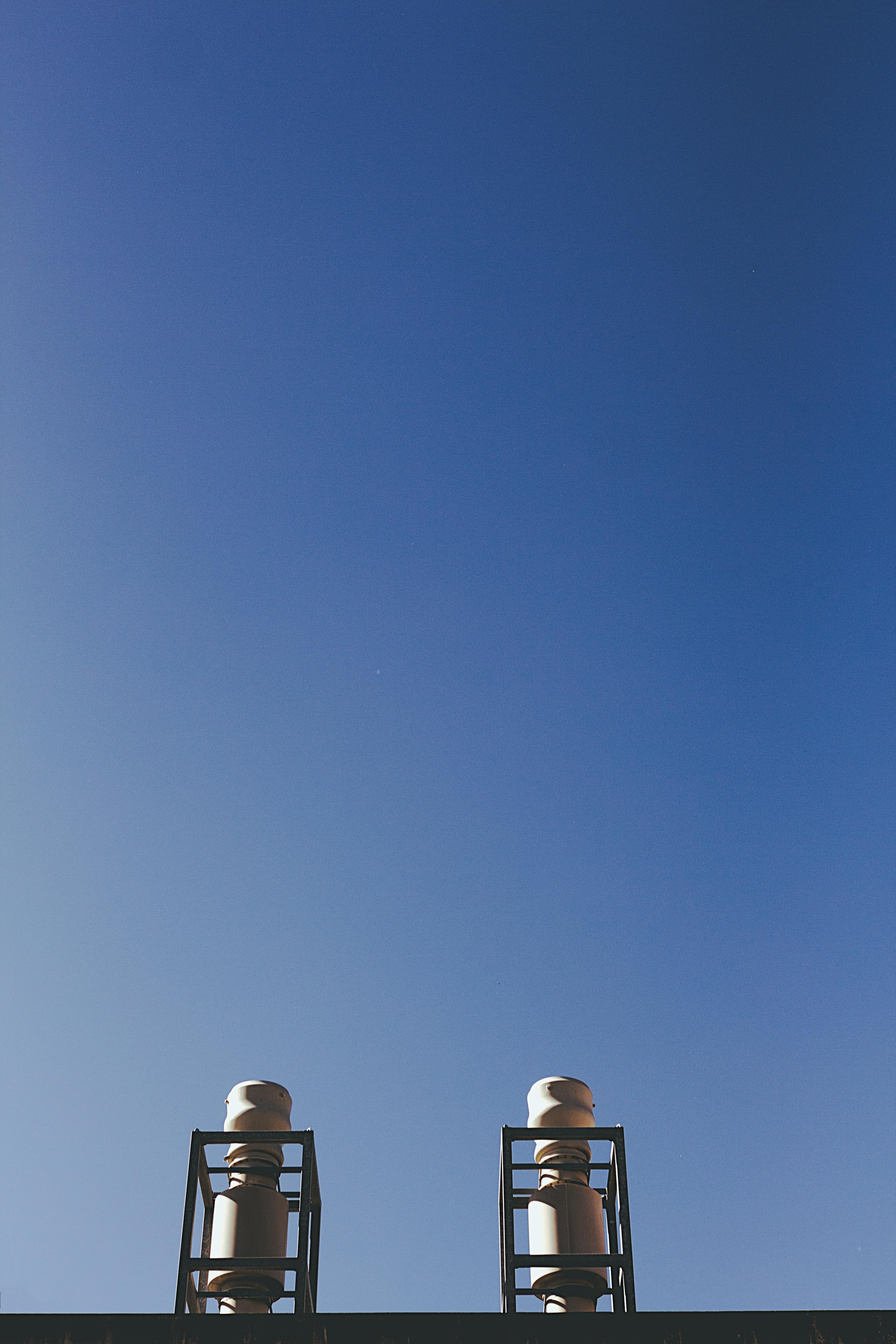 Low-angle shot of industrial building elements against a clear blue sky.