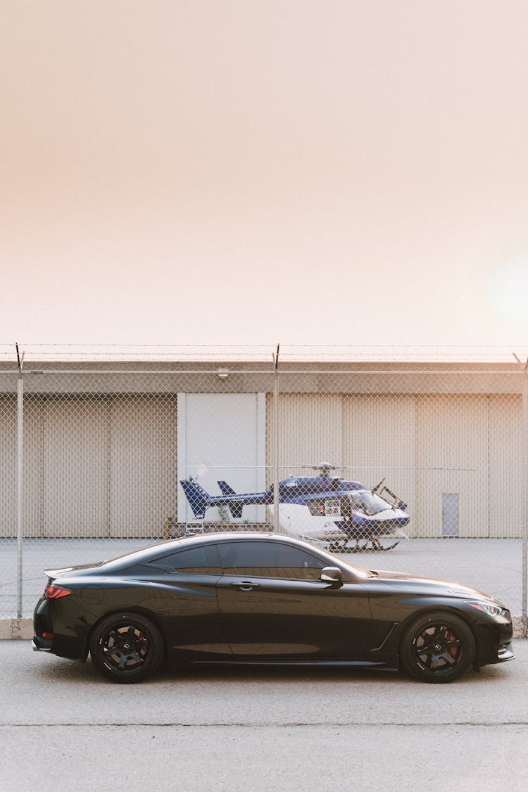 Black Coupe Parked Chain Link Fence