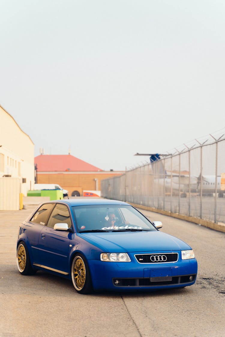 Person Driving A Blue Car Near Fence