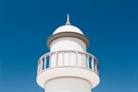 在清澈的蓝天下，矗立着一座极简主义的白色灯塔，展现了现代建筑的风格