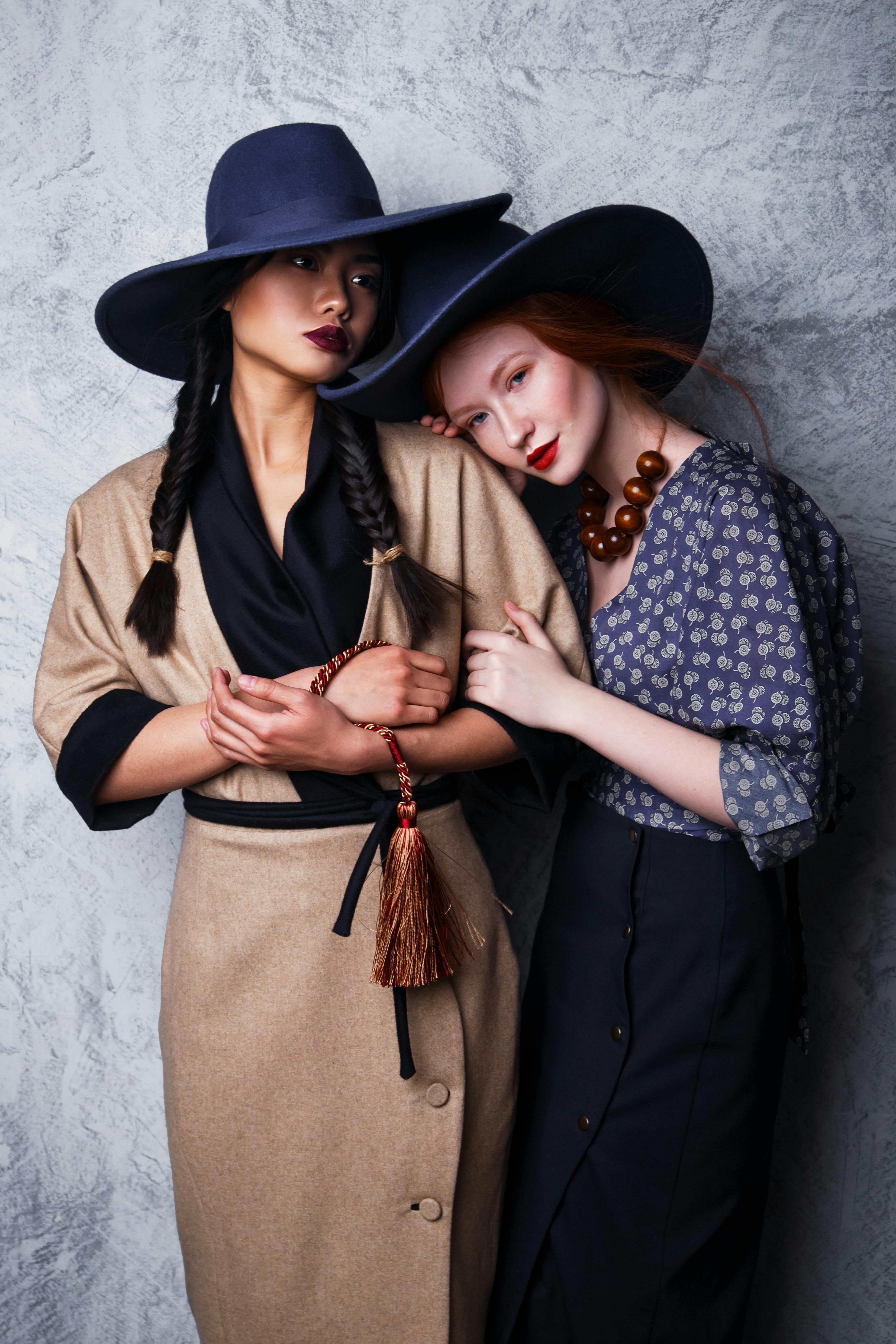 Stylish portrait of two women in fashionable hats and elegant clothing, exuding sophistication.