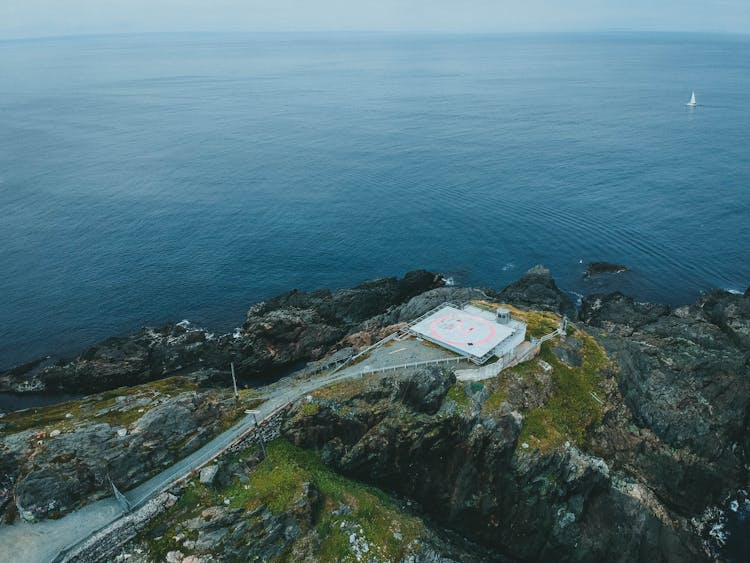 An Aerial View Of A Mountain Near The Ocean With A Helipad