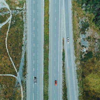 Drone shot of a highway with cars surrounded by green landscape, ideal for travel themes.