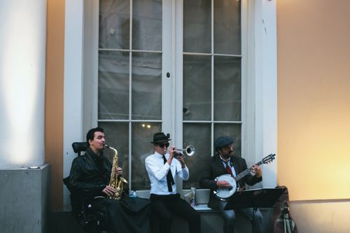 Free Three musicians play saxophone, trumpet, and banjo on the street, creating a vibrant jazz atmosphere. Stock Photo