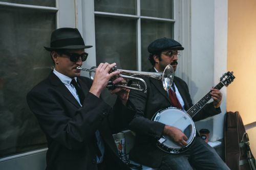 Free Two men perform jazz music with a trumpet and banjo on a street corner, capturing a vintage vibe. Stock Photo