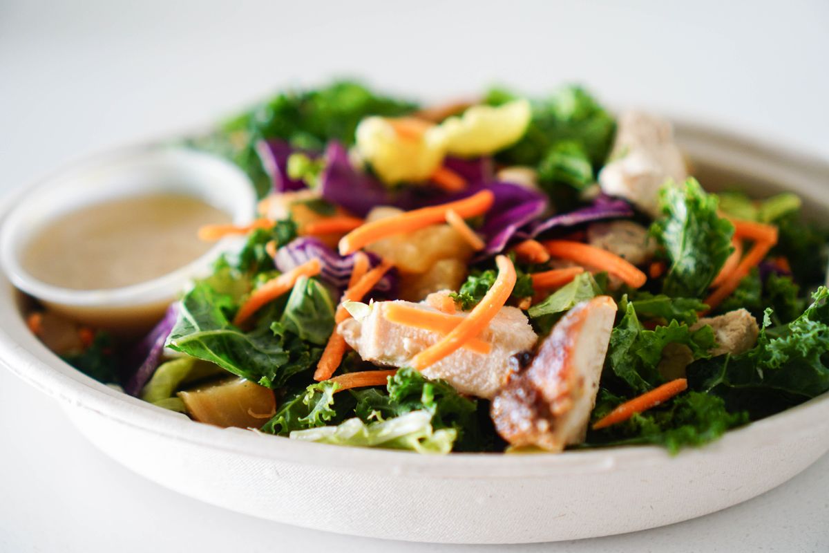 Kale and red cabbage salad with grilled chicken, shredded carrots and vinaigrette cup