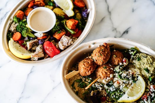 Top view of two vibrant Mediterranean bowls featuring fresh vegetables and falafel.