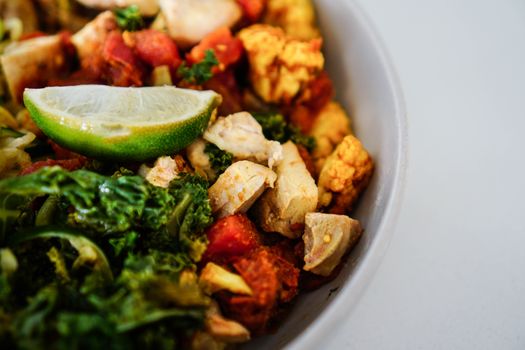 Vibrant salad with chicken, kale, and lime in a bowl, offering a healthy and colorful dish.