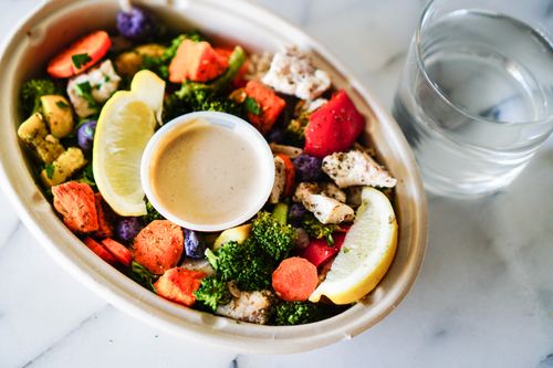 Free Healthy mixed salad with chicken, lemon, and dip on marble. Stock Photo