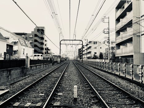 Monochrome view of train tracks flanked by buildings in Nagawa, Japan.