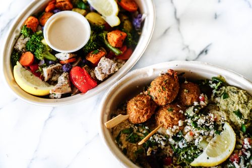 Free Vibrant Mediterranean dishes featuring falafel skewers with fresh vegetables and hummus in bowls. Stock Photo