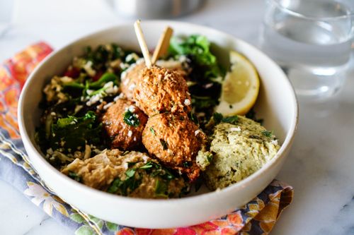 Free Tasty Mediterranean falafel bowl with fresh greens, a lemon slice, and hummus. Stock Photo