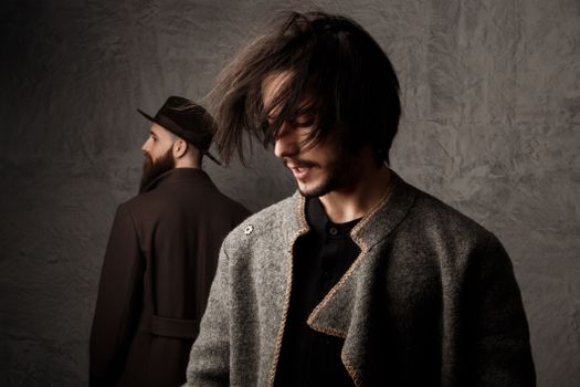 Fashion shoot featuring two men in stylish winter coats and hats, set in Milan studio.