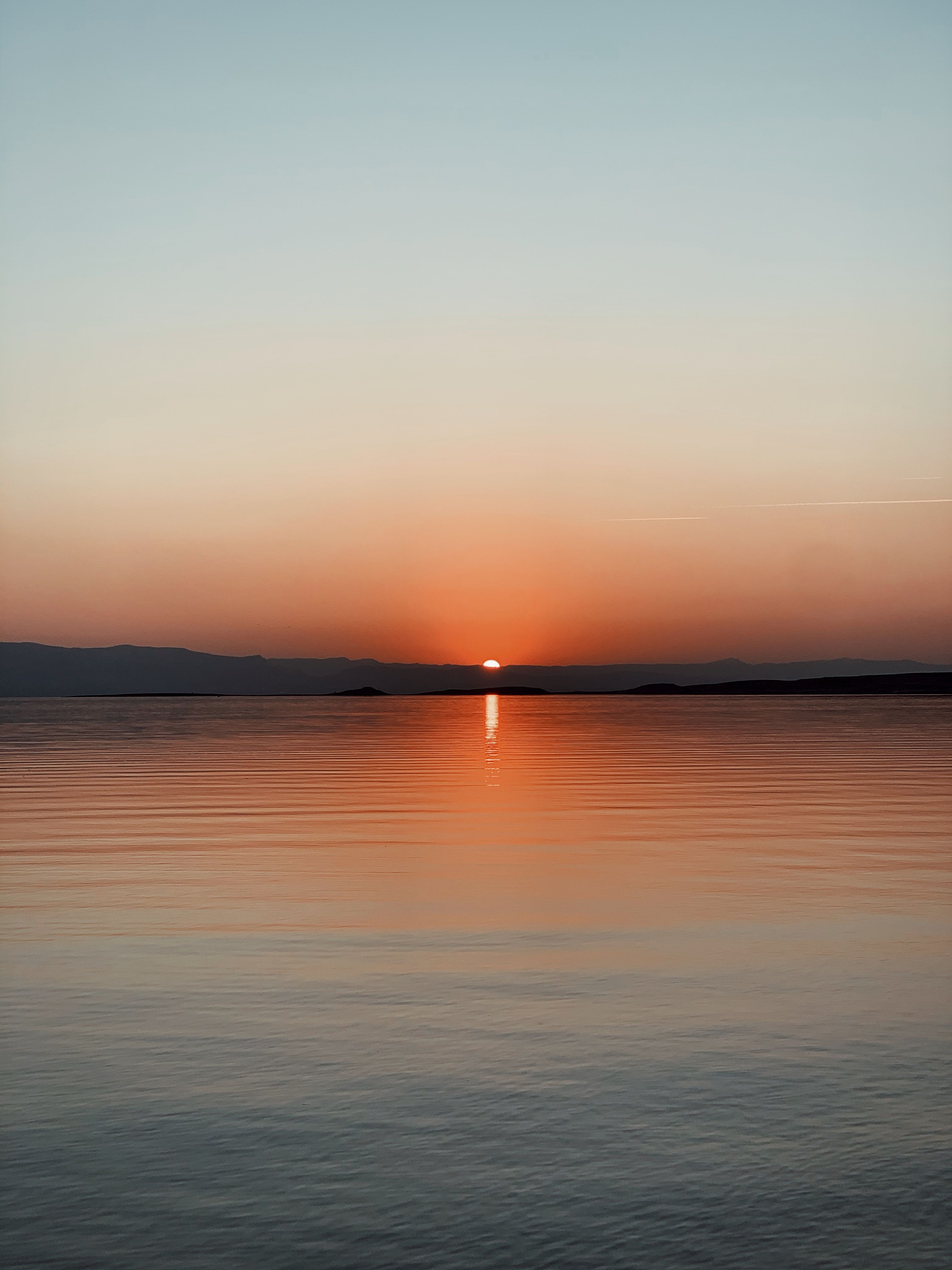 Spectacular scenery of calm water of river under cloudless colorful sky at sunrise