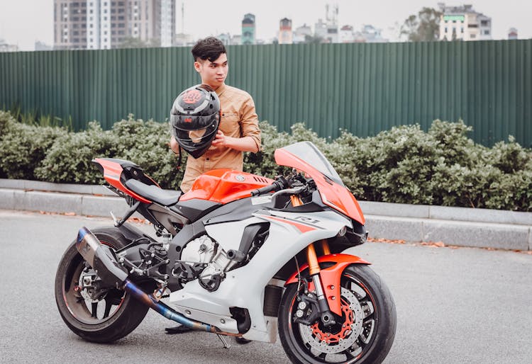 A Man Standing Near The Big Bike While Holding His Helmet