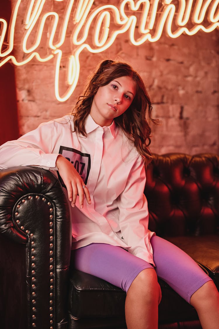 A Woman In White Long Sleeves And Purple Cycling Shorts Sitting On A Leather Couch