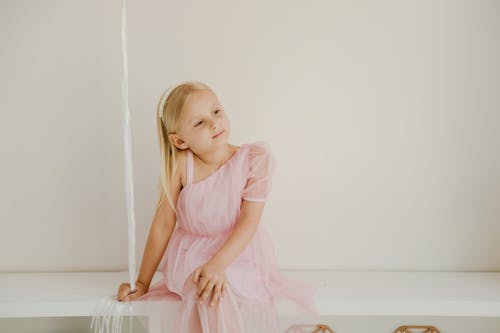 Free Girl Wearing Pink Dress Sitting on a Counter Stock Photo