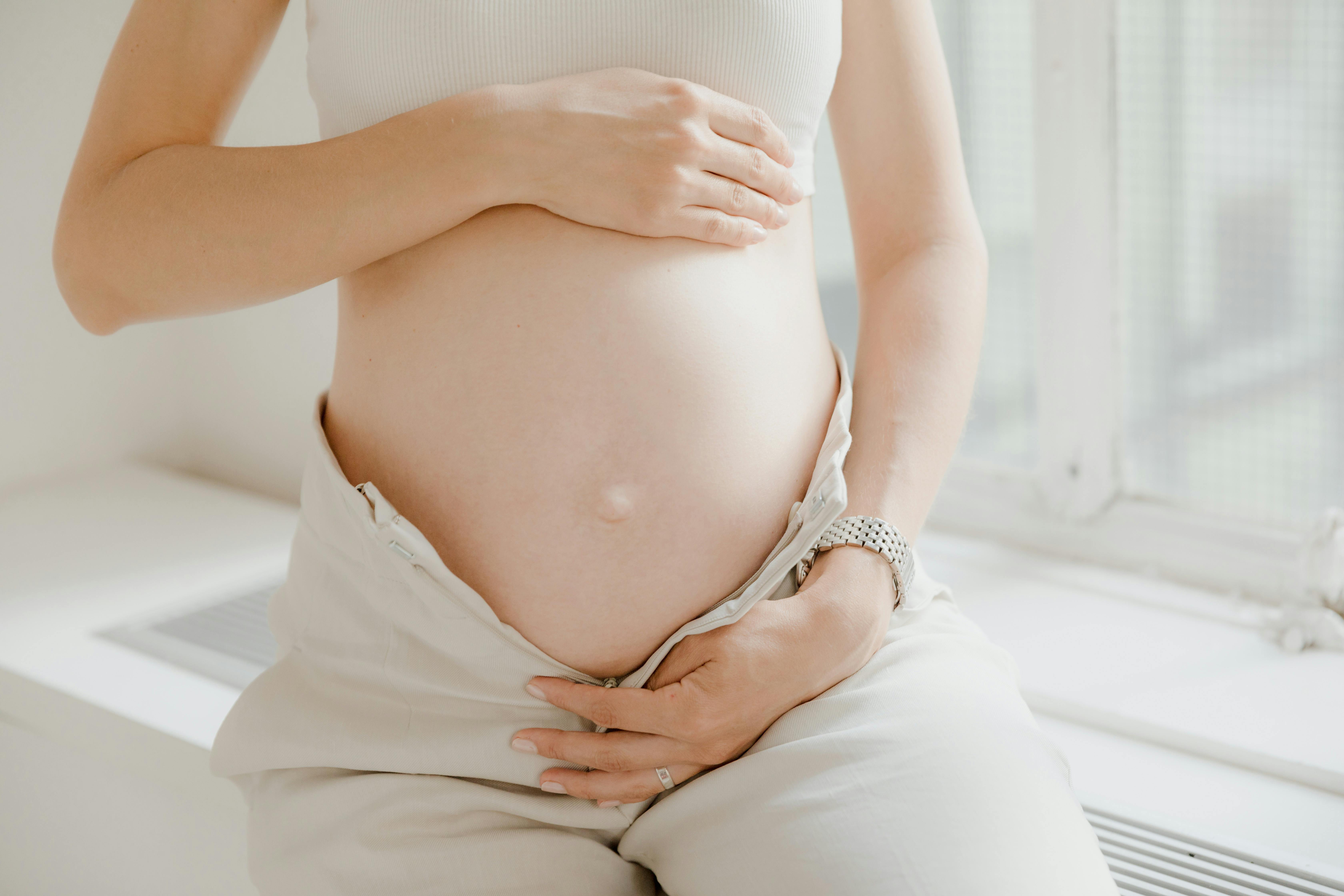 a pregnant woman in white top and white pants