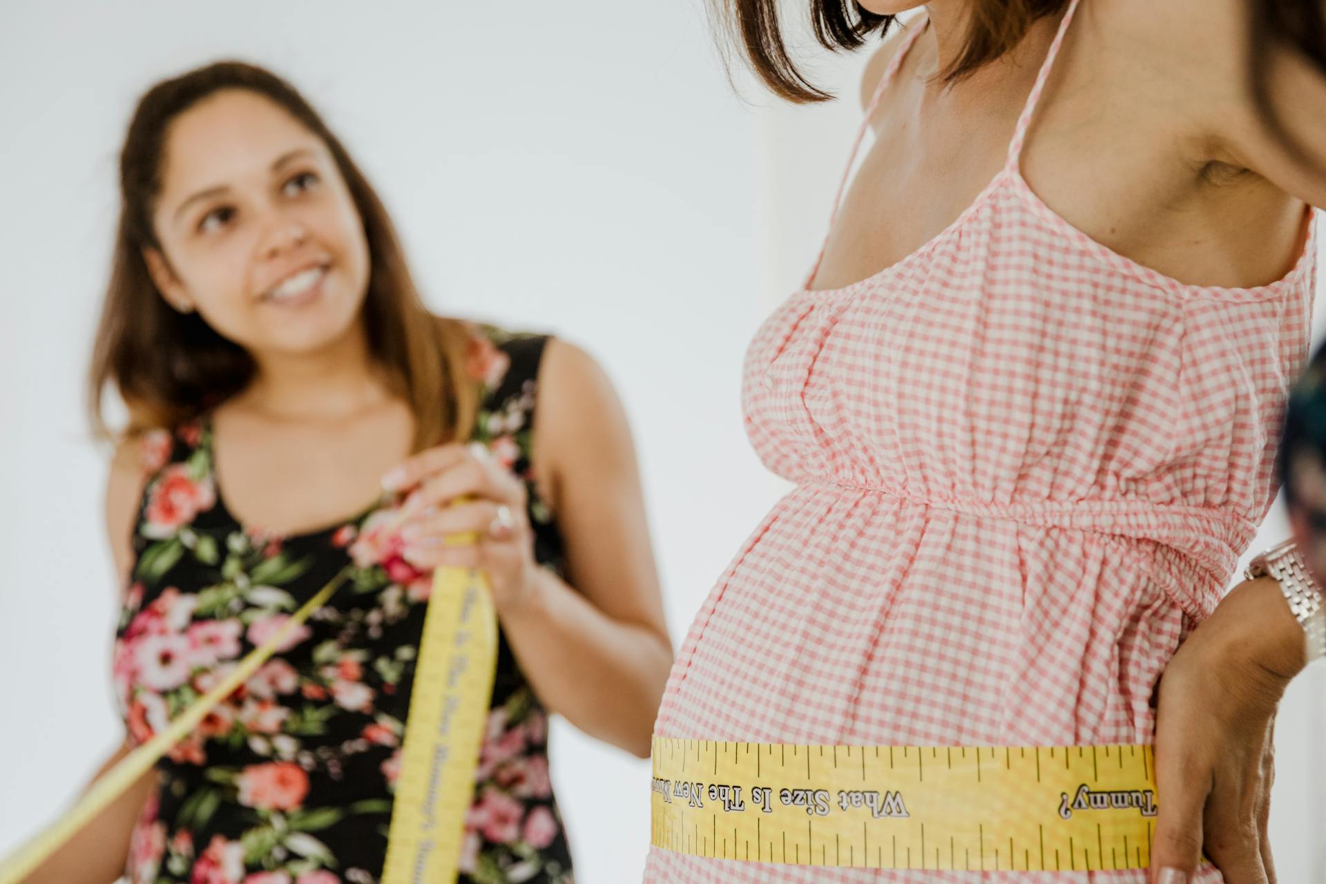 A Pregnant Woman Holding Yellow Tape Measure Around her Belly