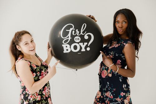 Free Two women holding a gender reveal balloon, celebrating the anticipation of a newborn. Stock Photo