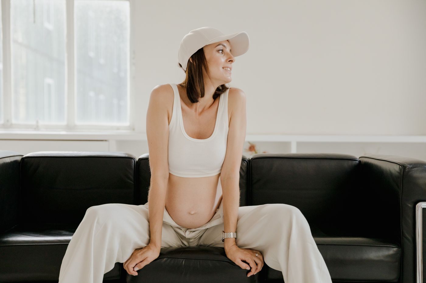 Future maman assise confortablement dans un salon à la lumière naturelle