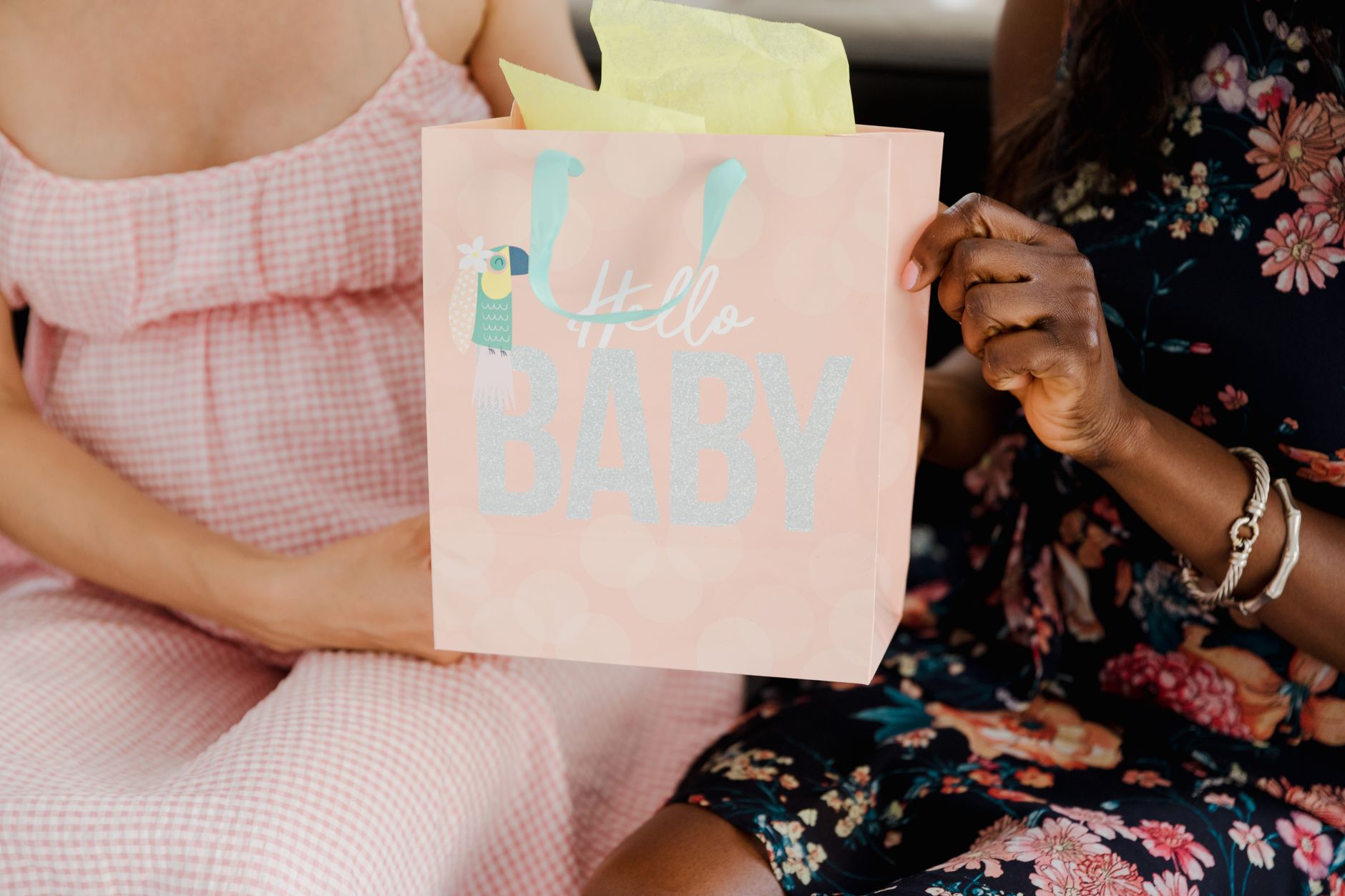 Close-up of a pregnant woman sitting with a baby shower gift bag, celebrating motherhood.