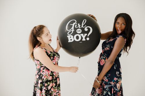 Free Two women celebrating a gender reveal with a decorative balloon, expressing excitement and joy. Stock Photo