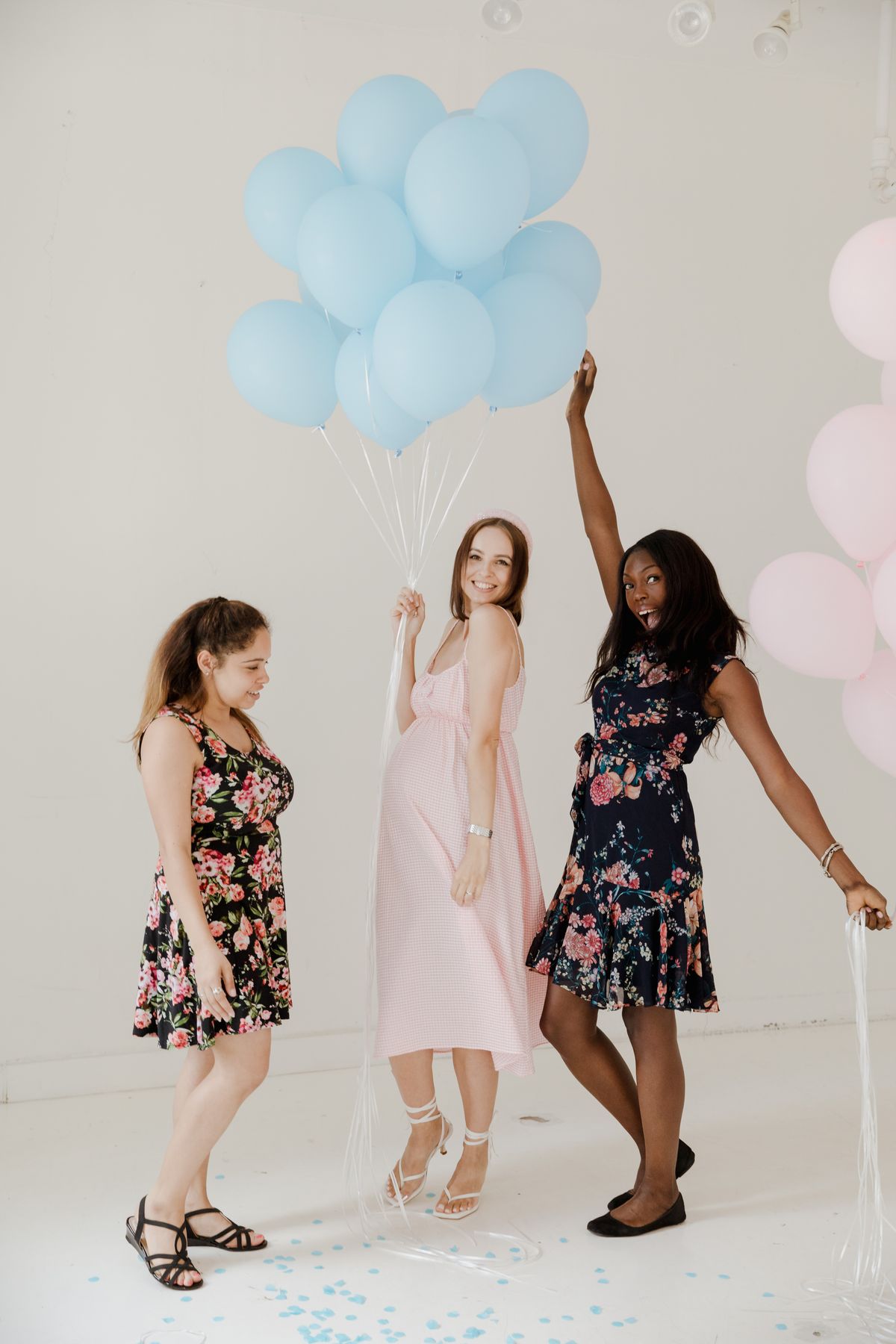 Frauen feiern eine Gender Reveal Party mit rosa und blauen Ballons