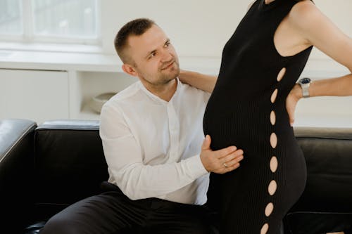 Pregnant Woman in Black Dress Standing in Front of a Man