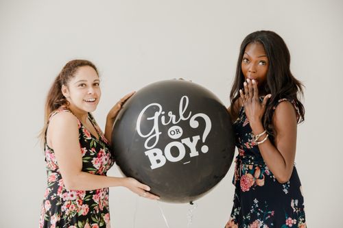 Free Two women holding a 'Girl or Boy?' balloon, celebrating a gender reveal. Stock Photo