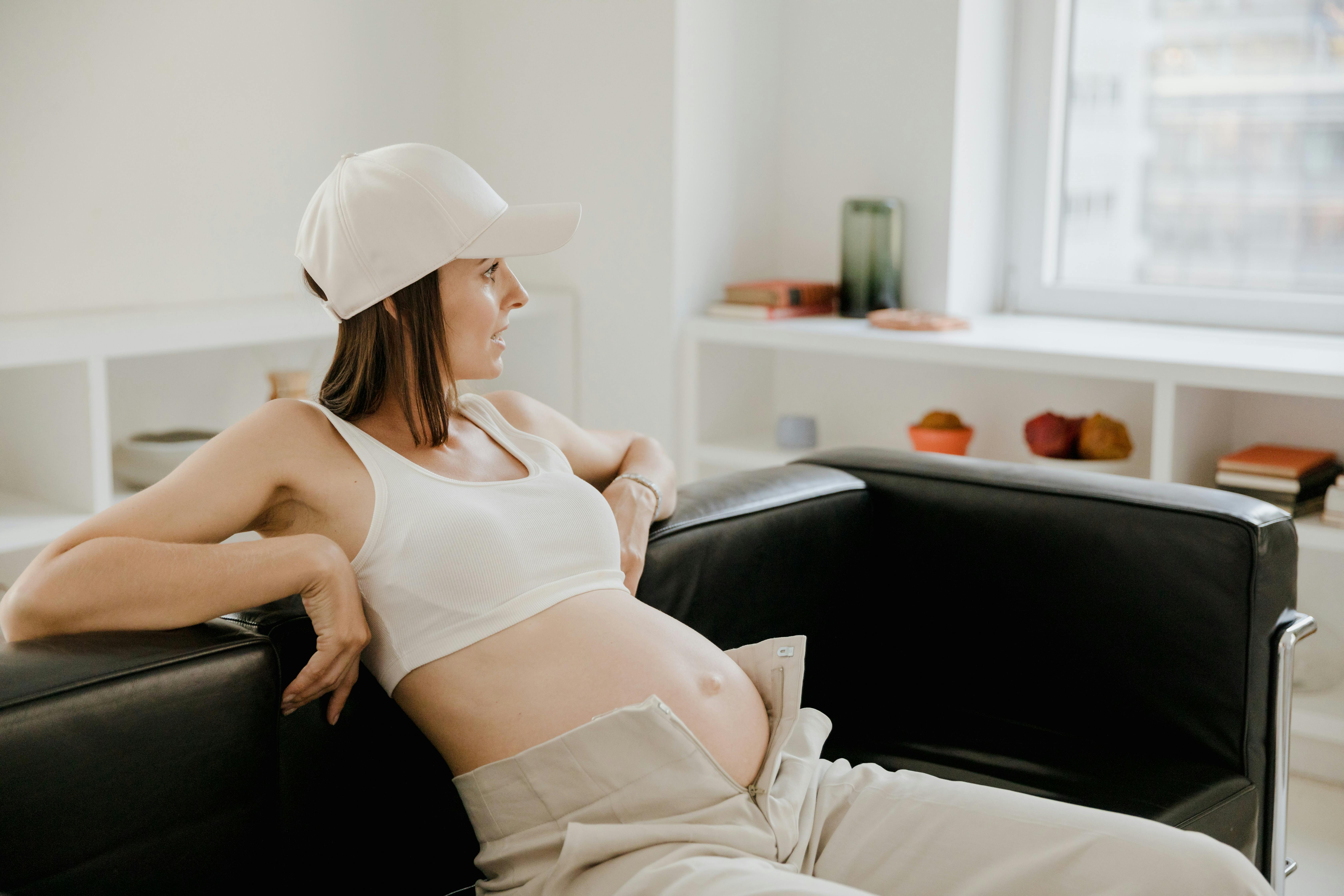 pregnant woman in casual clothes sitting on sofa