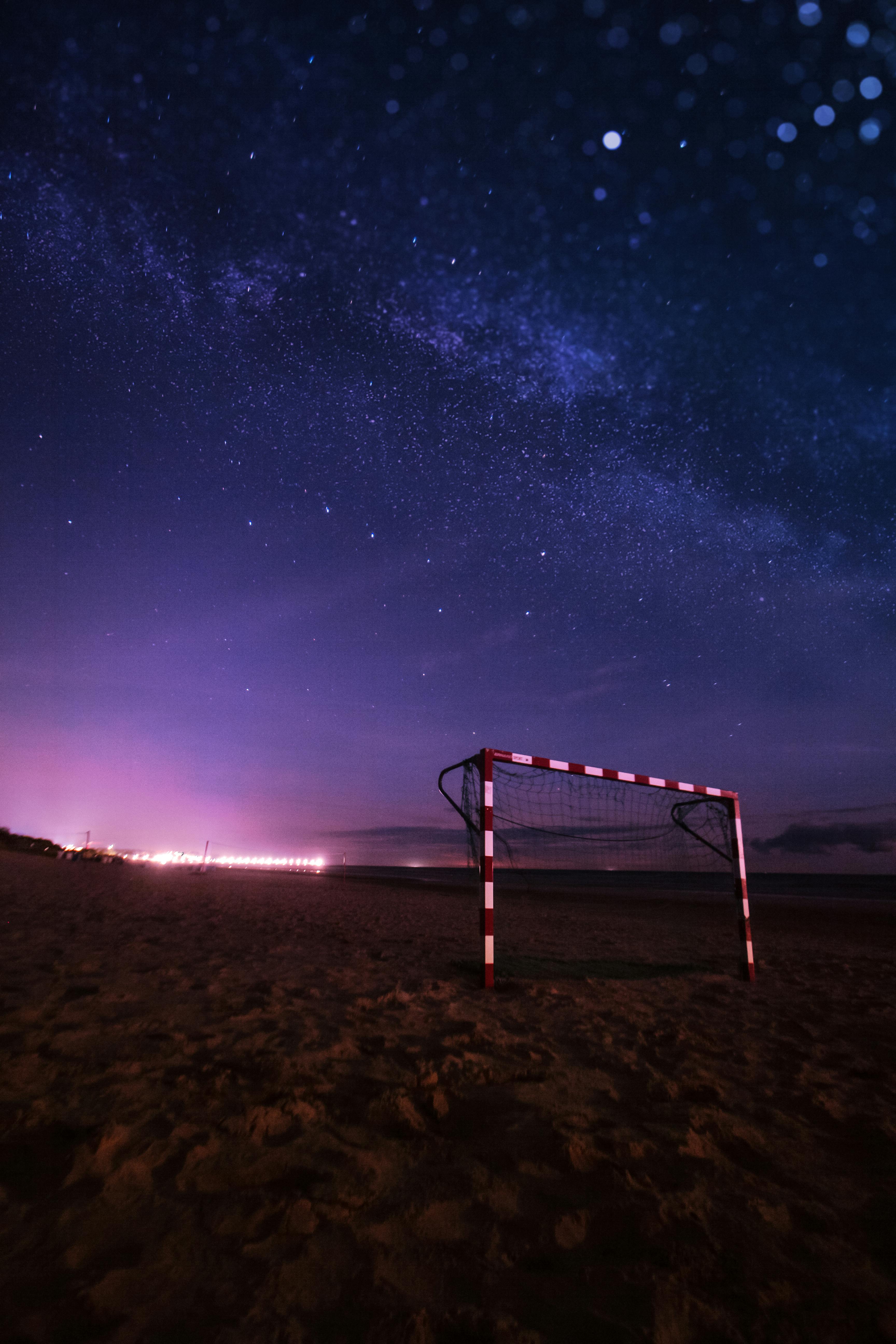 A mesmerizing night view of a soccer goal under a starry sky on a beach by the Baltic Sea.