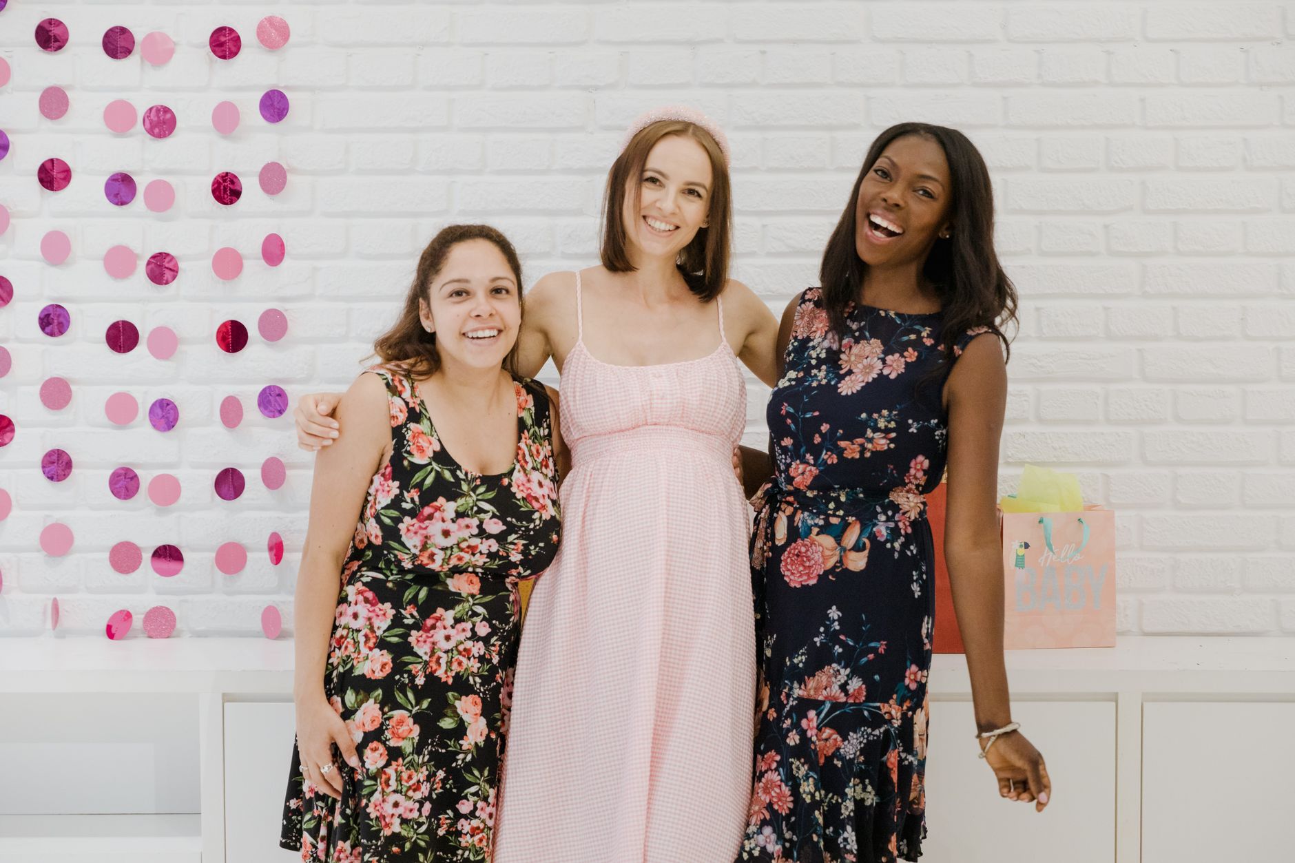 Three women celebrating a baby shower, showcasing friendship and happiness indoors.