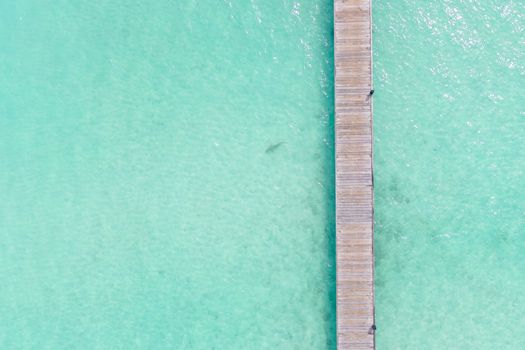A stunning aerial view of a wooden dock extending over clear turquoise waters in the Maldives, perfect for travel inspiration.