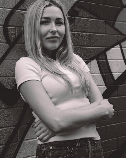 Woman in Pink T-shirt Leaning on Brick Wall