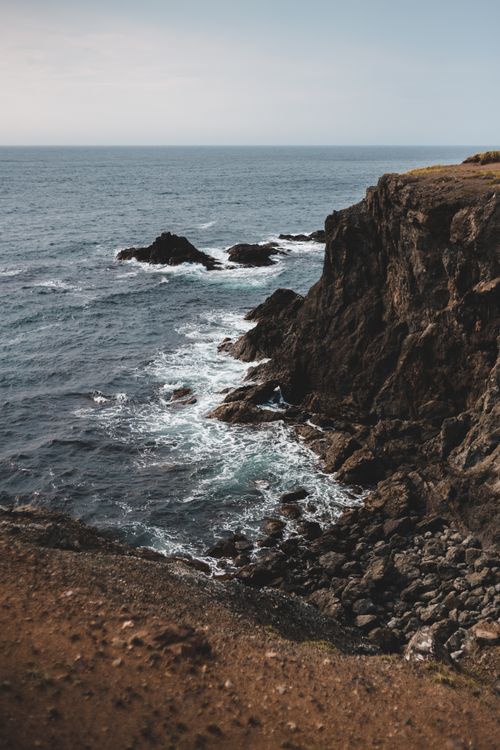 Free Breathtaking view of rugged seaside cliffs with waves crashing below under a clear sky. Stock Photo