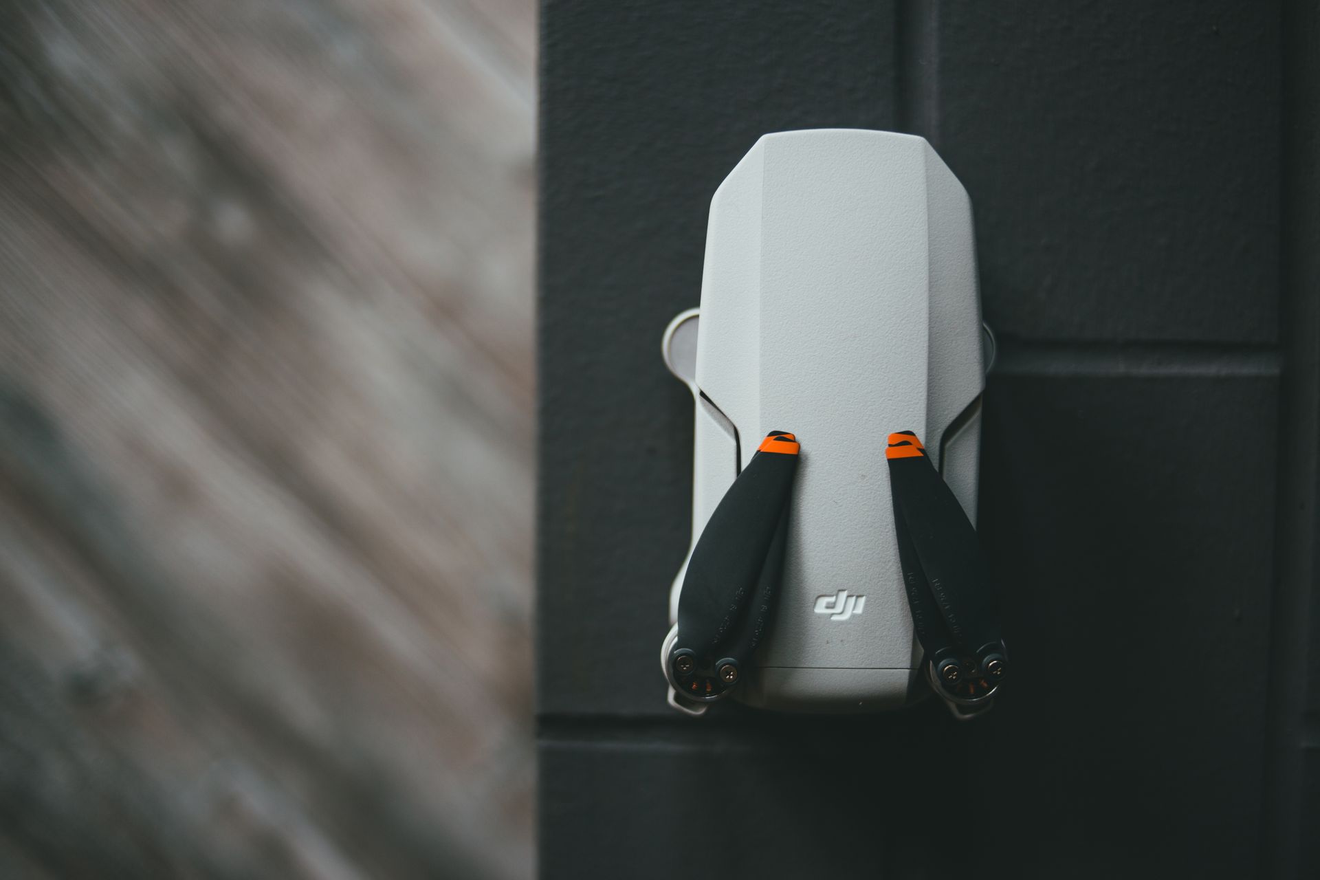 A modern white drone is mounted on a dark wall, showcasing its compact design and technology.