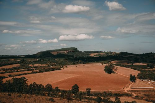 Free A panoramic aerial shot of a vast rural landscape with hills and trees under a cloudy sky. Stock Photo