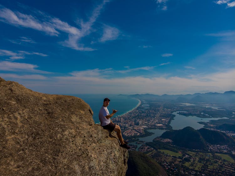 A Man Sitting On A Cliff In Pedra Gavea