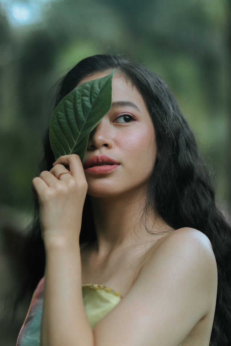 Beautiful Young Woman Holding A Leaf Against Her Eye 