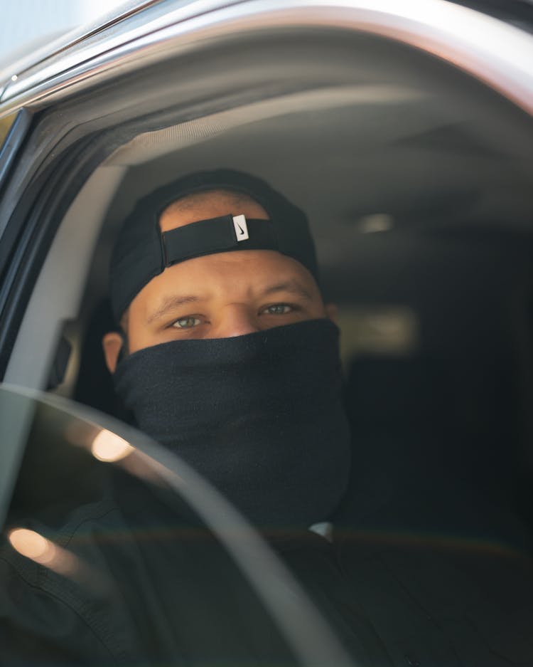 Man In Face Mask In Car Window