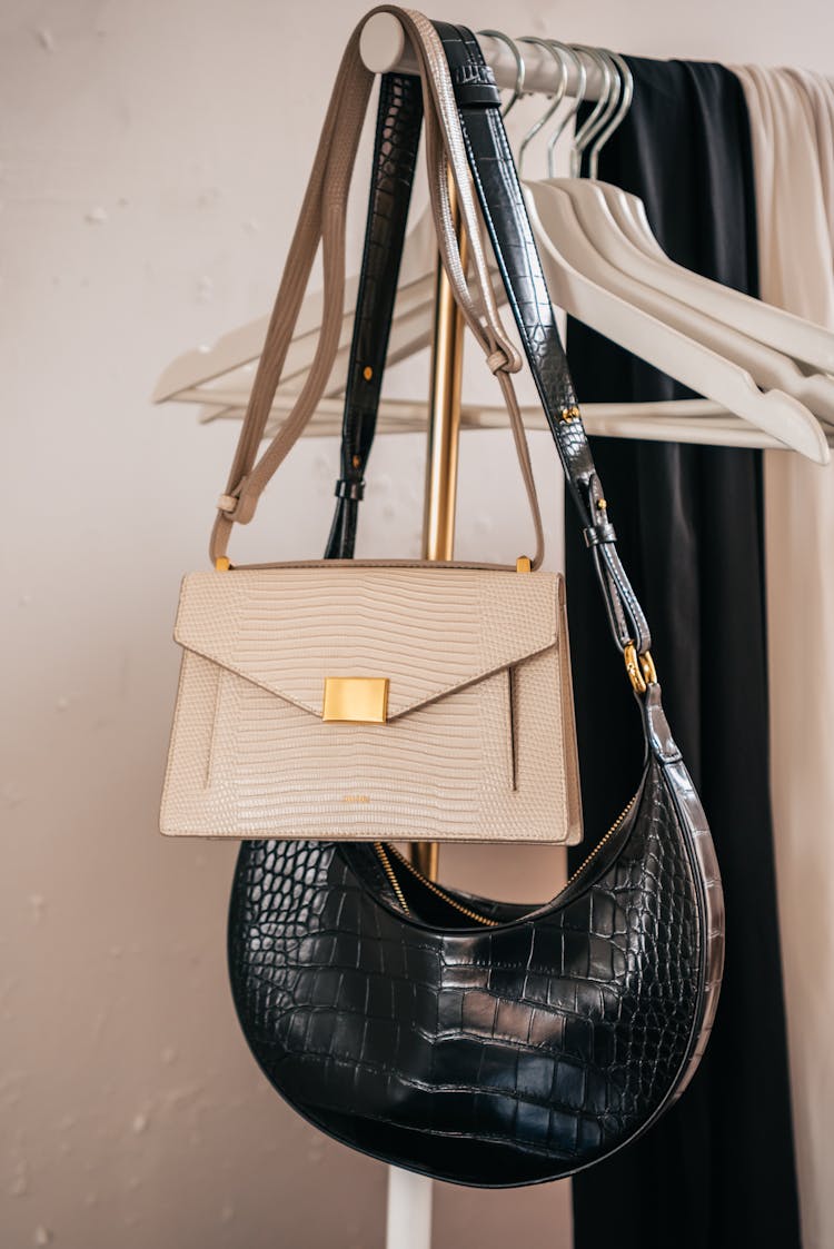 Black And White Leather Shoulder Bags Hanging On A Clothing Rack